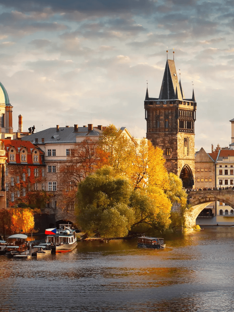 Historic Prague river scene with Charles Bridge and Gothic tower in autumn.