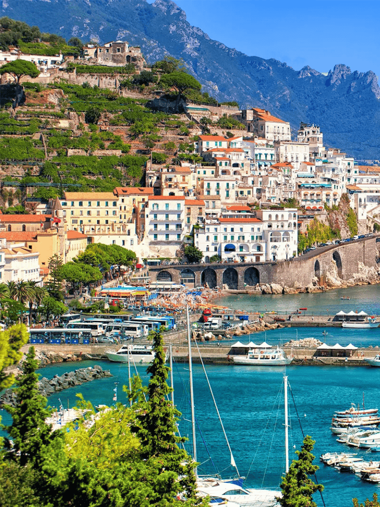 Picturesque Amalfi Coast village with colorful buildings, lush greenery, and vibrant harbor in Italy.