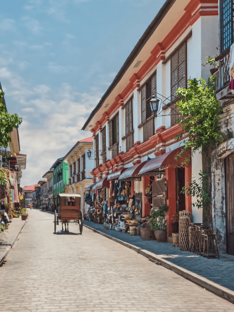 Colorful historic street with shops and a rickshaw, vibrant atmosphere, traditional architecture, and lively commerce in a charming city.