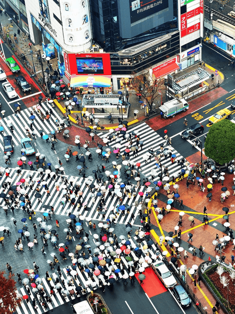 Crowded city crosswalk with people holding umbrellas in downtown urban area.