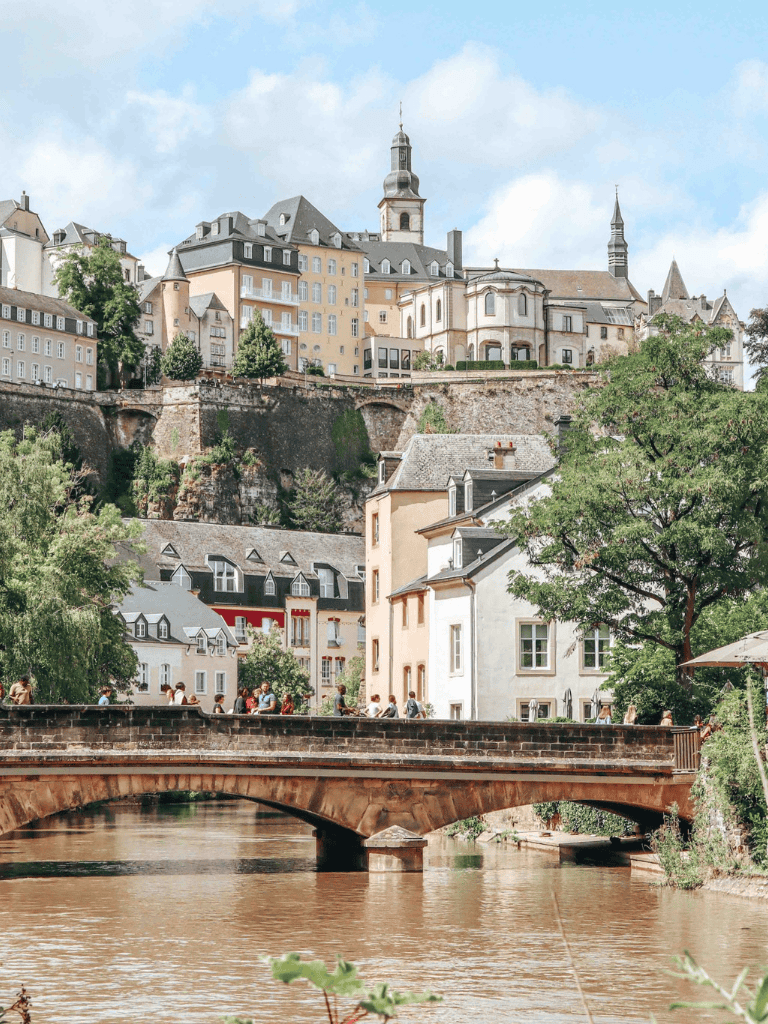 Picturesque European hillside cityscape with historic buildings and a river bridge, perfect for travel and sightseeing.