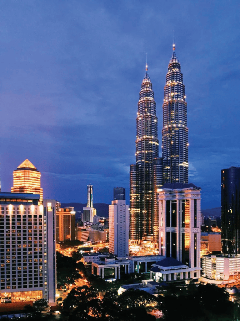 Petronas Towers Kuala Lumpur city skyline illuminated at night, Malaysia iconic landmark.