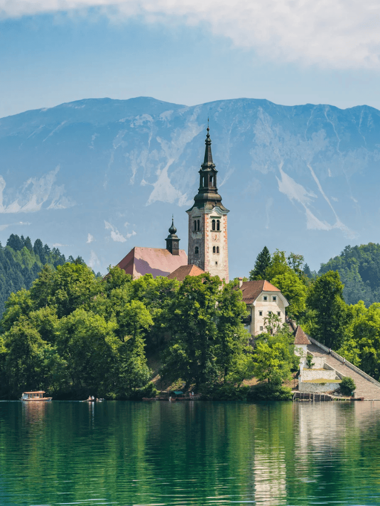 Scenic view of Lake Bled with Bled Island and the Church of the Assumption, surrounded by lush greenery and mountains.