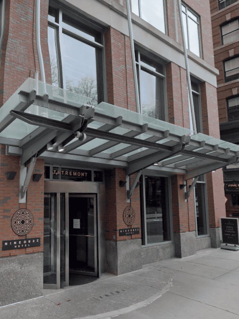 Modern hotel entrance with glass canopy in downtown Minneapolis, featuring brick facade and stylish signage.