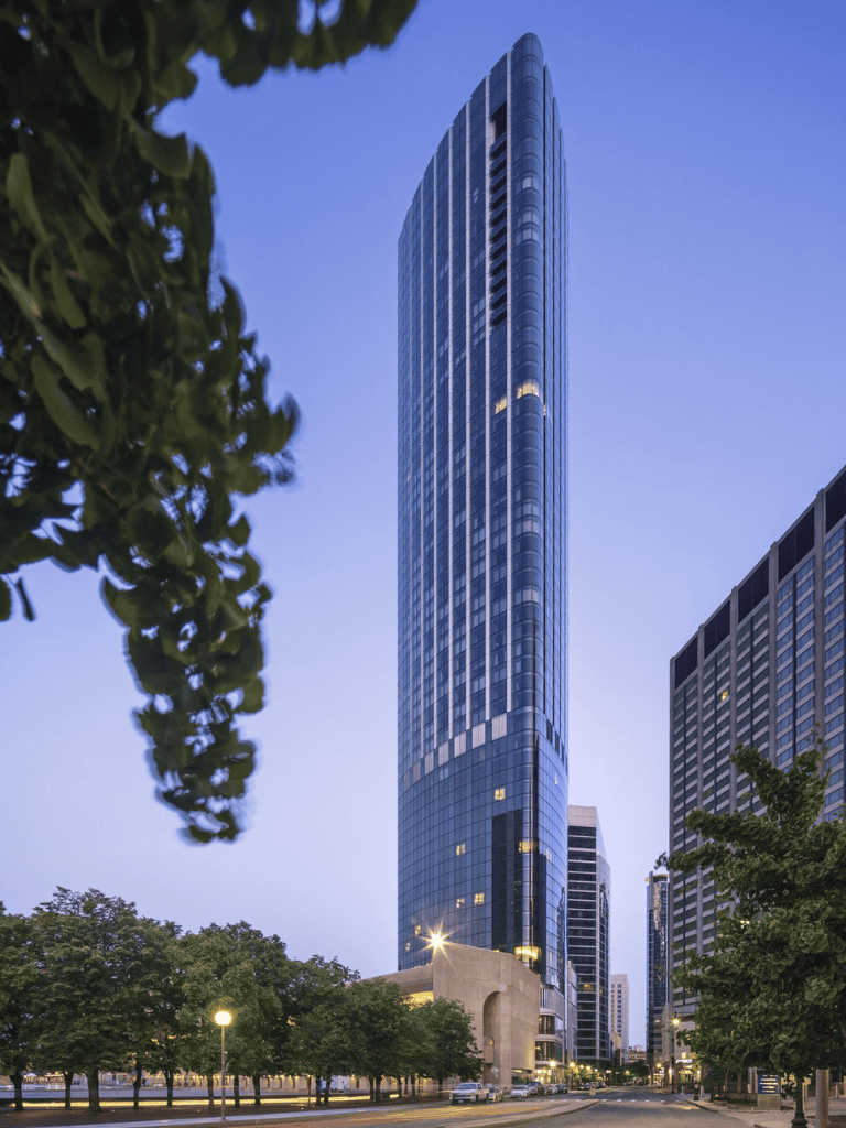 Modern city skyscraper with glass facade at dusk, representing urban architecture and development.
