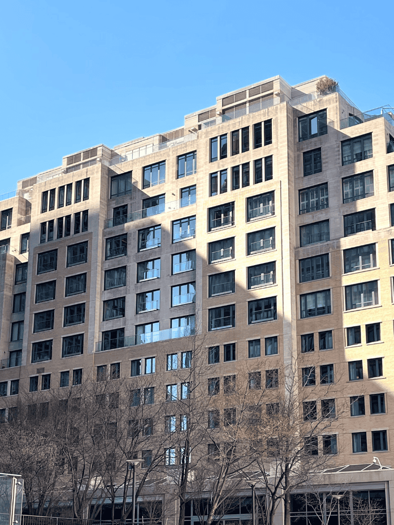 Modern residential apartment building with large windows and urban skyline.