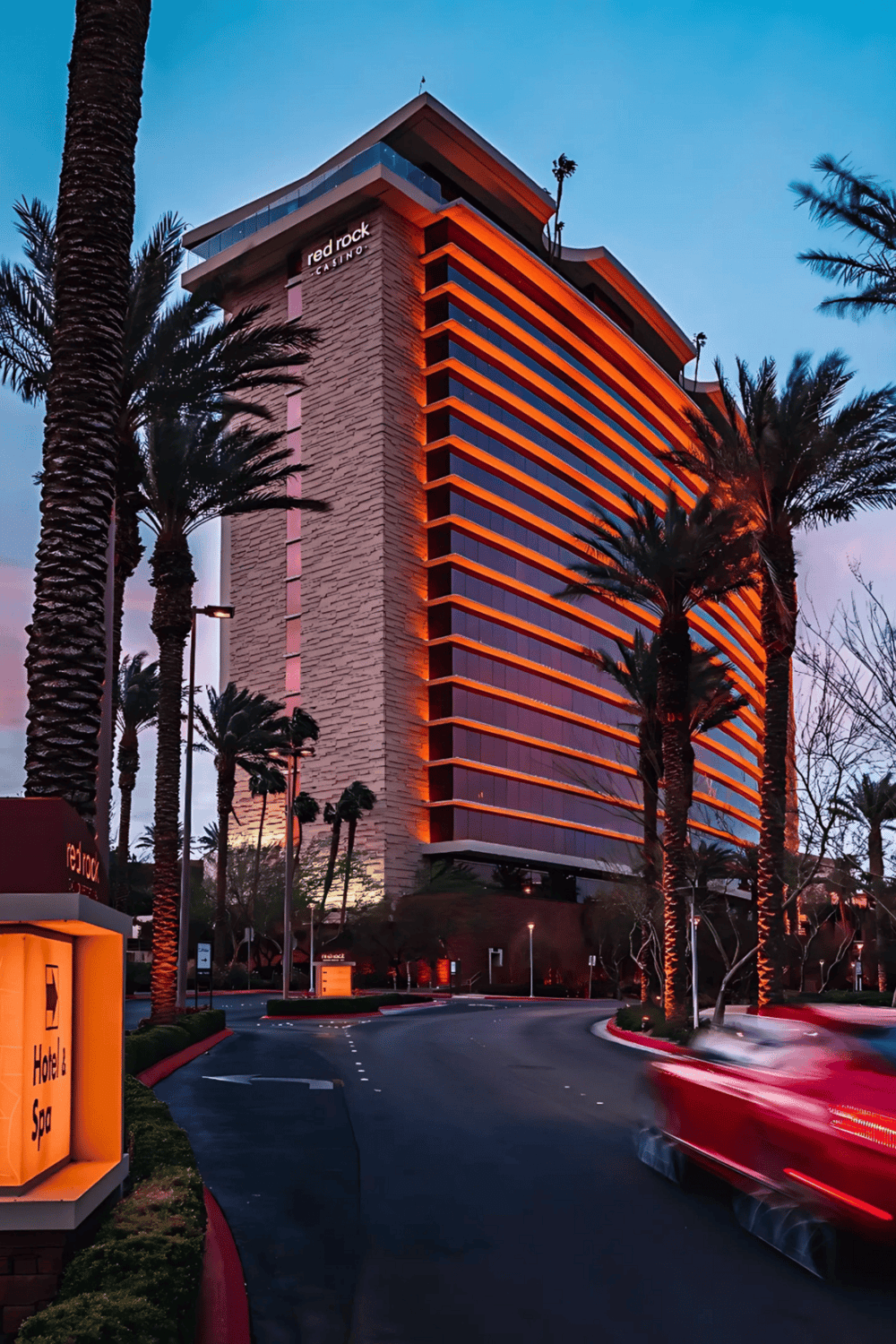 Luxurious Red Rock Casino hotel at dusk with illuminated exterior and palm trees in Las Vegas.