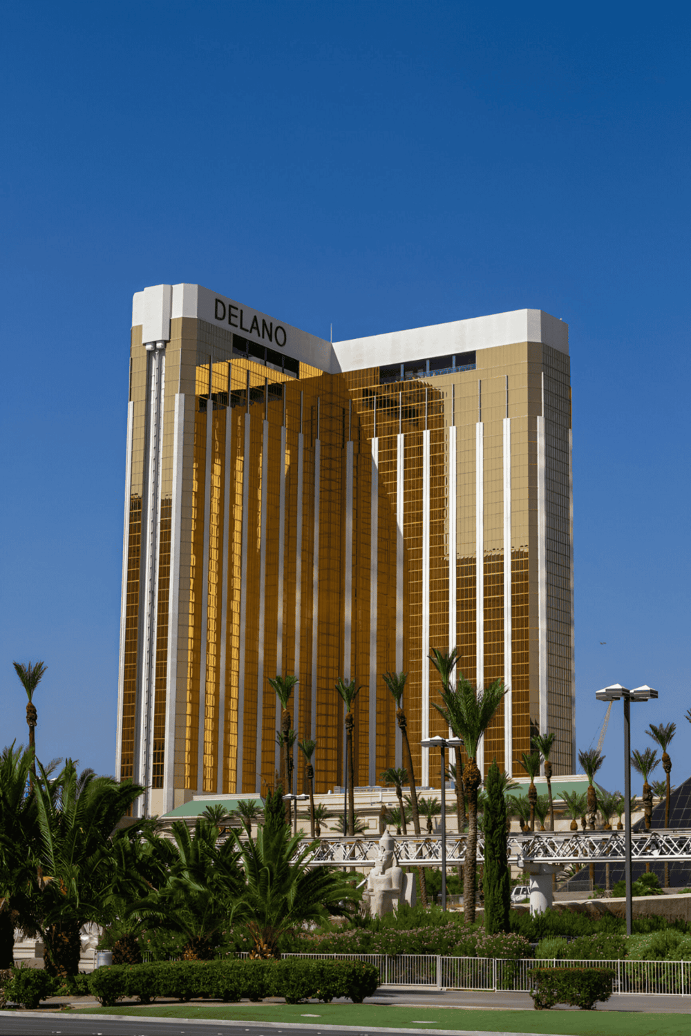Luxurious Delano Hotel in Las Vegas with gold-tinted skyscraper and palm trees.