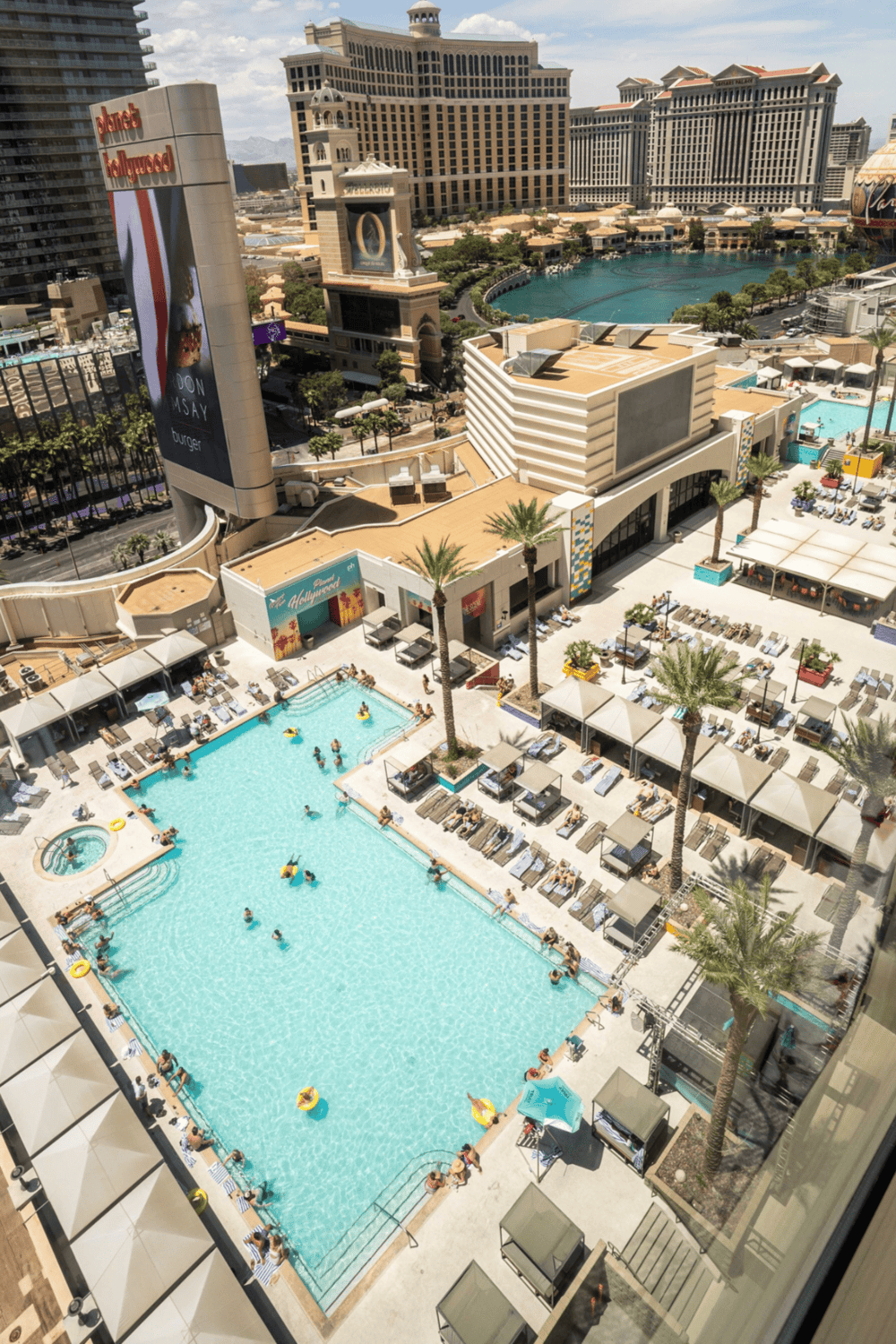 Las vegas luxurious hotel pool with iconic city skyline view and entertainment venues.