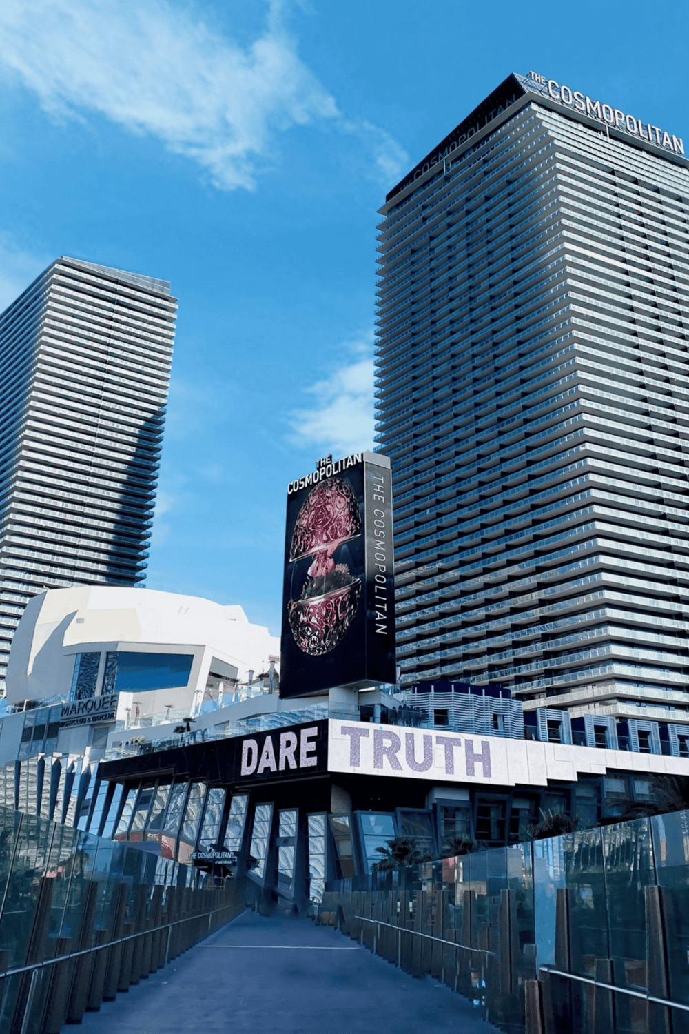 Modern skyscrapers at The Cosmopolitan hotel in Las Vegas with vibrant signage and clear blue sky.