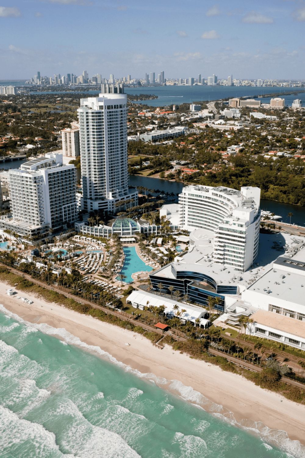 Luxurious beachfront hotel with pool in Miami Beach, Florida, showcasing city skyline views.