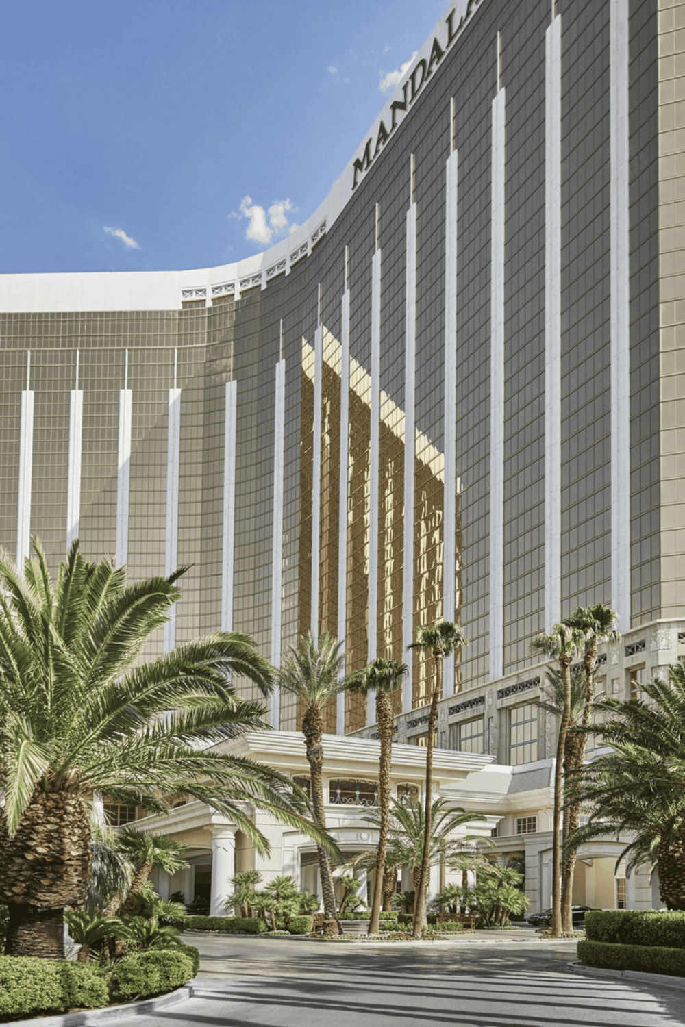 Modern luxury hotel with palm trees in front, featuring reflective glass architecture.
