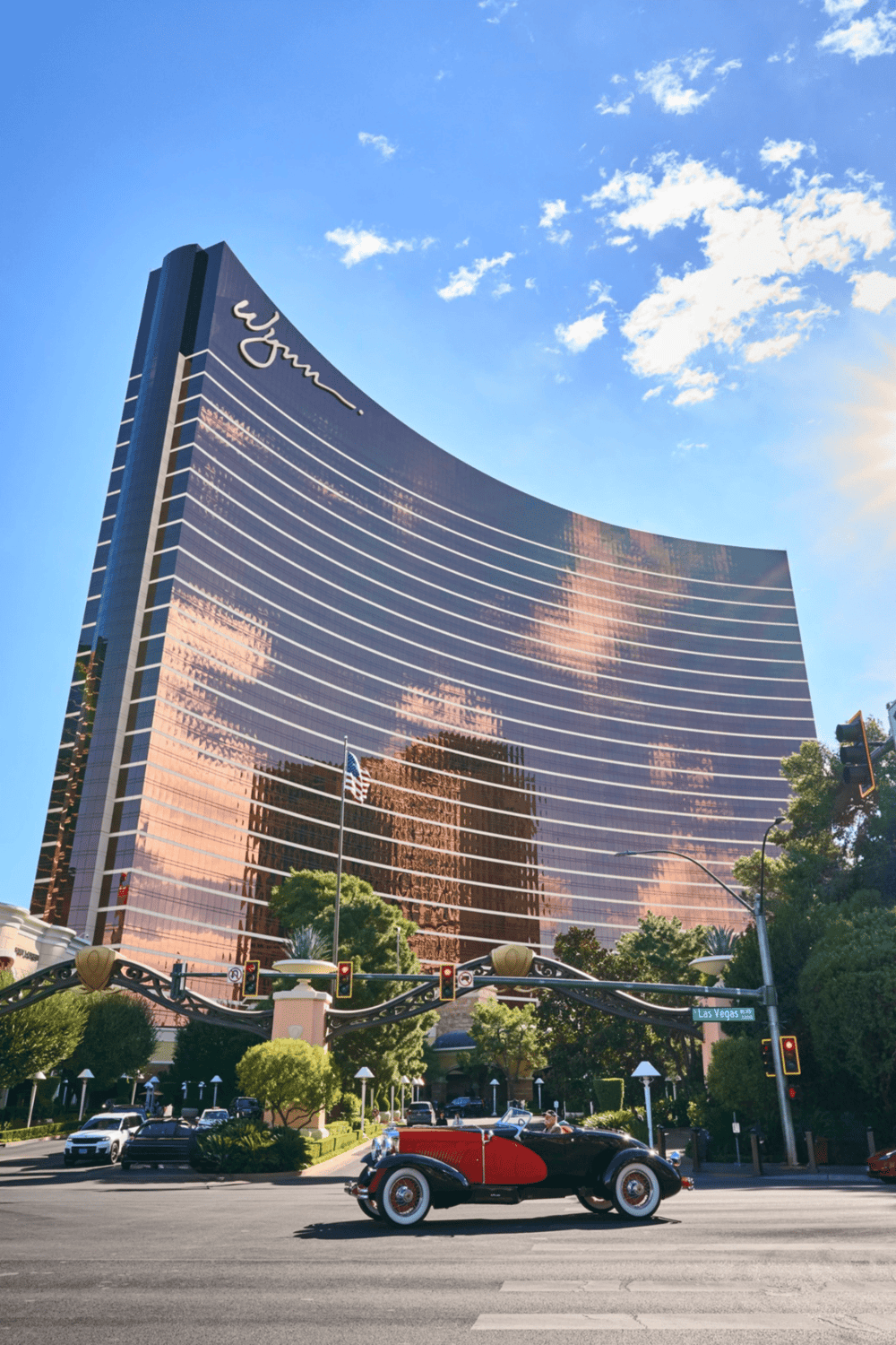 Luxurious Wynn hotel in Las Vegas with reflective glass exterior and classic vintage car in front.