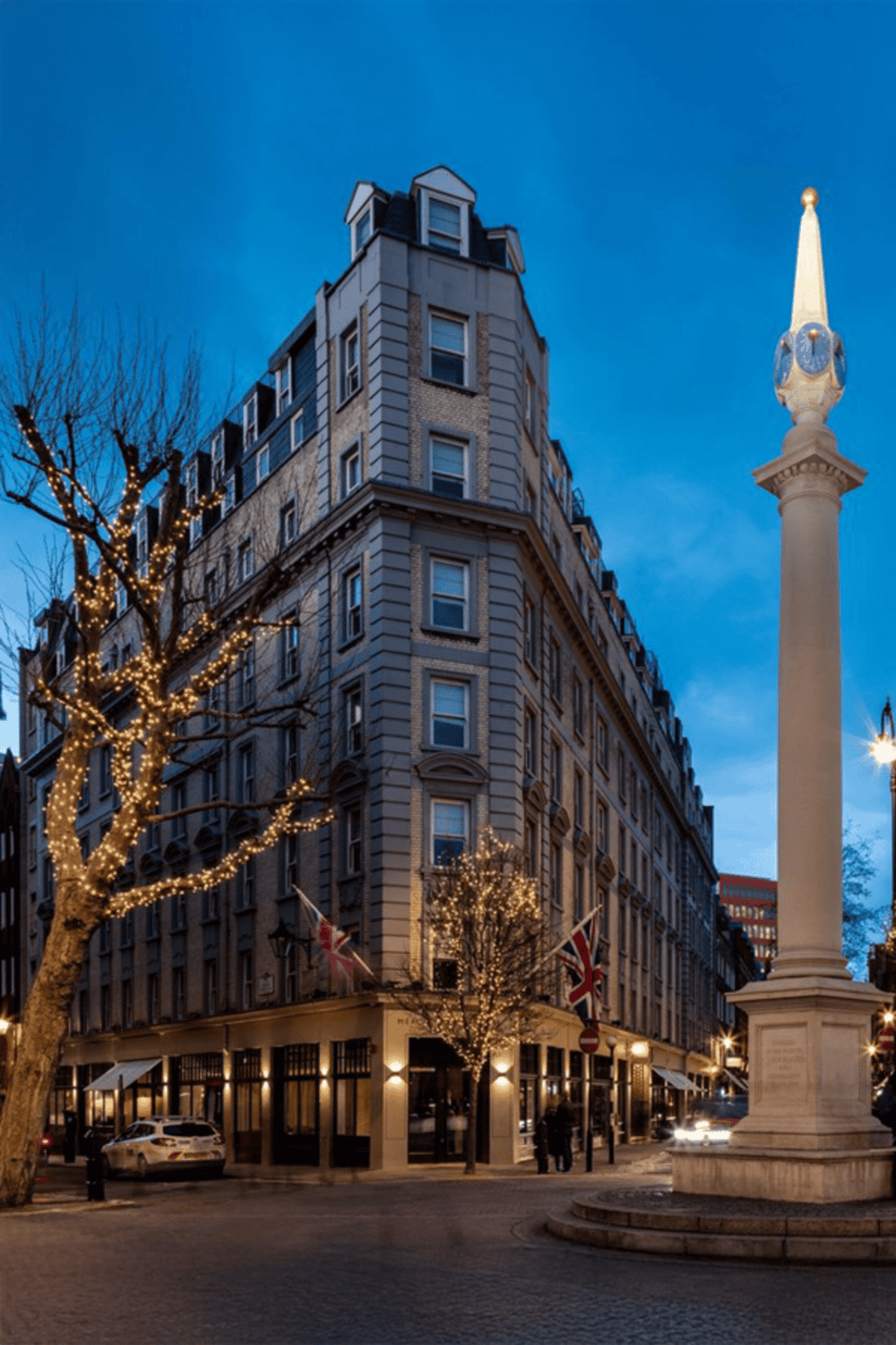 Downtown London building with festive holiday lights and British flags, scenic evening cityscape.