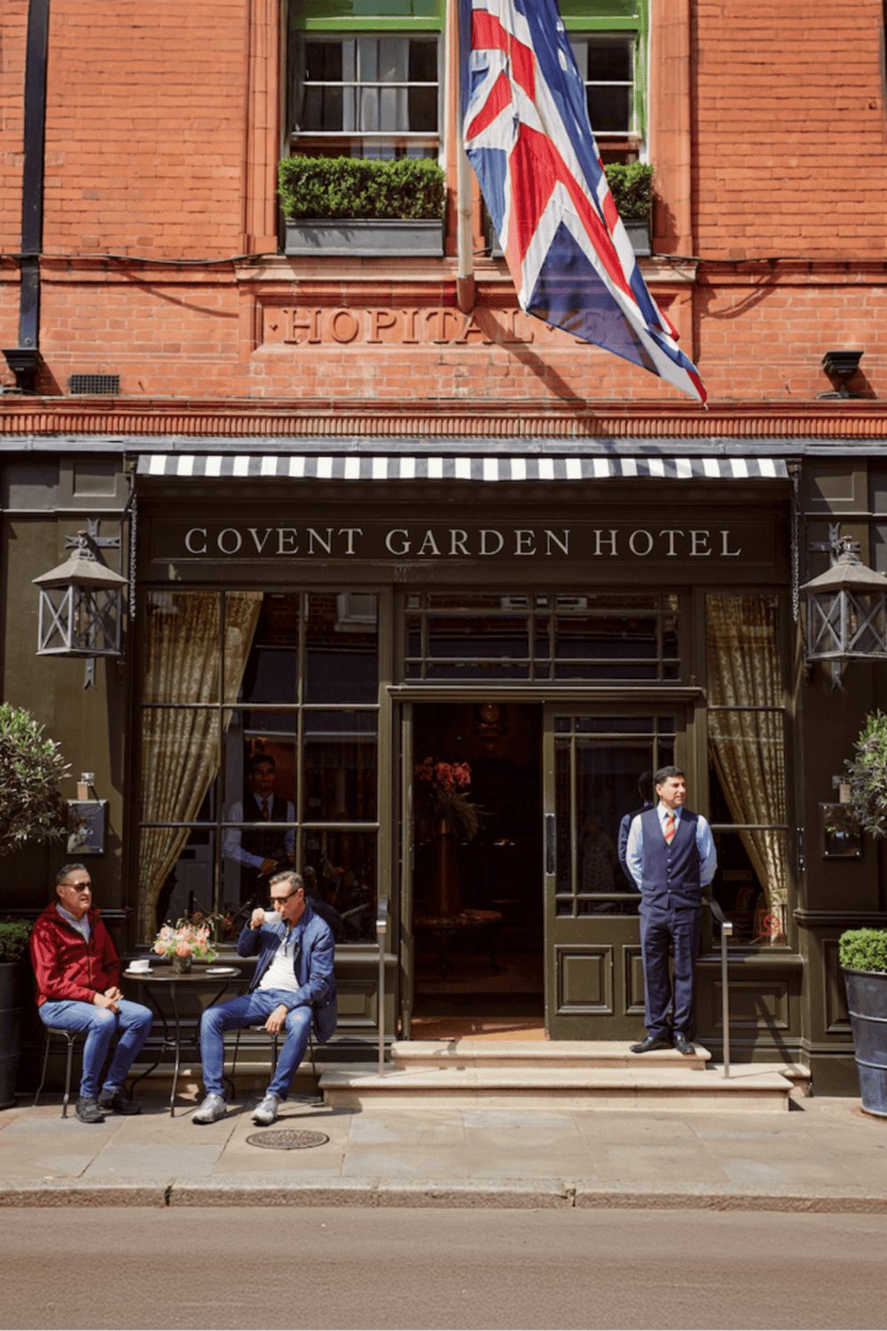 Covert Garden Hotel entrance with outdoor seating, British flag, and welcoming staff, ideal for travelers seeking comfortable accommodations.