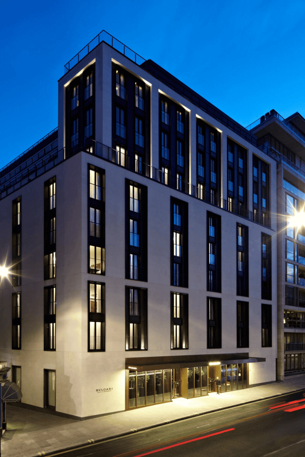 Luxurious modern hotel building with illuminated windows at night, cityscape view.