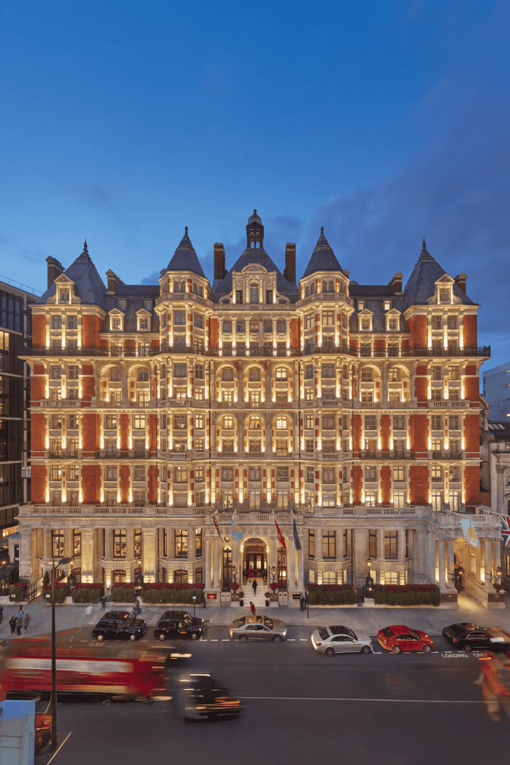 Grand historic hotel with elegant architecture and night illumination in a city street scene.