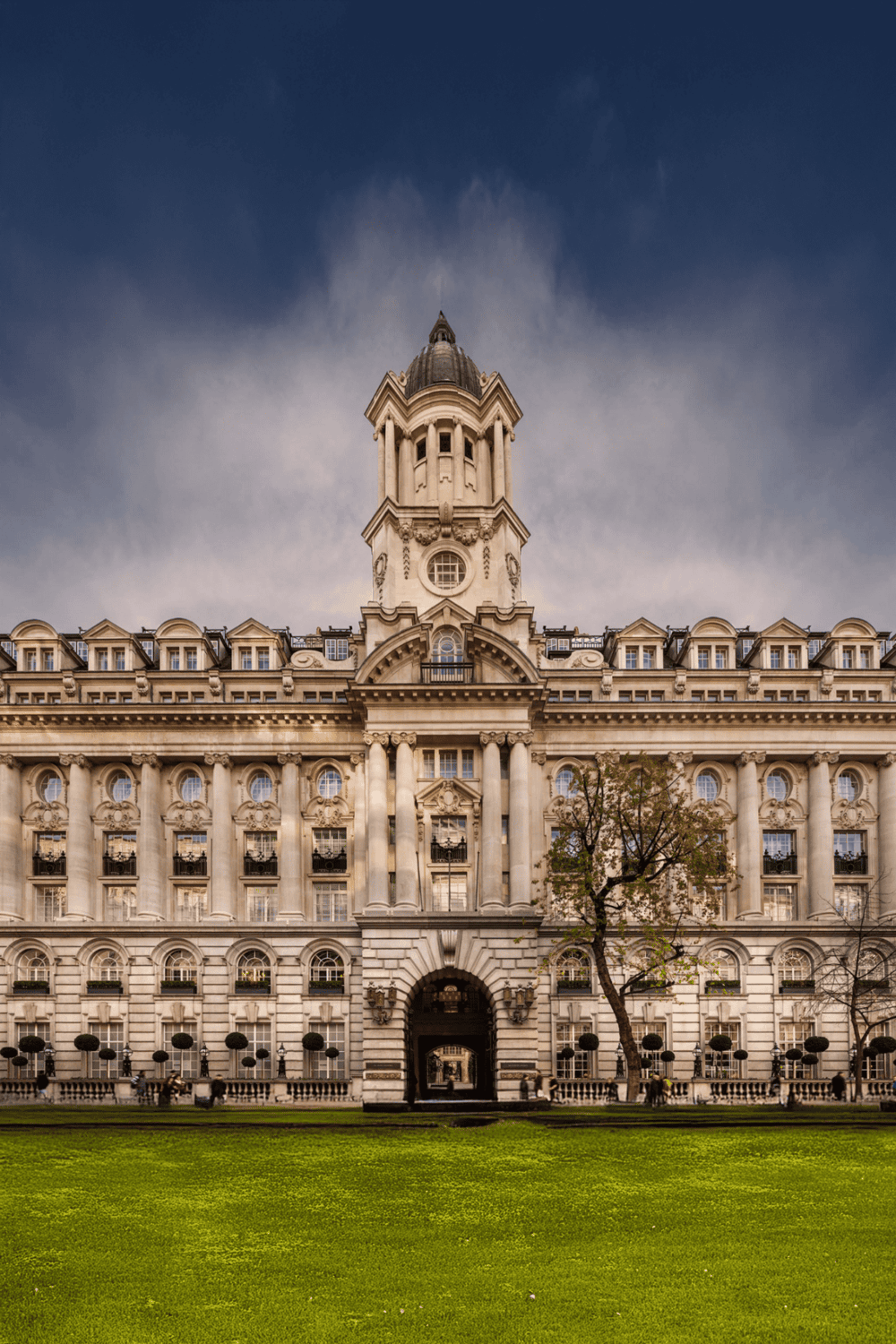 Grand historic hotel building with ornate architecture and clock tower, located in a city park.