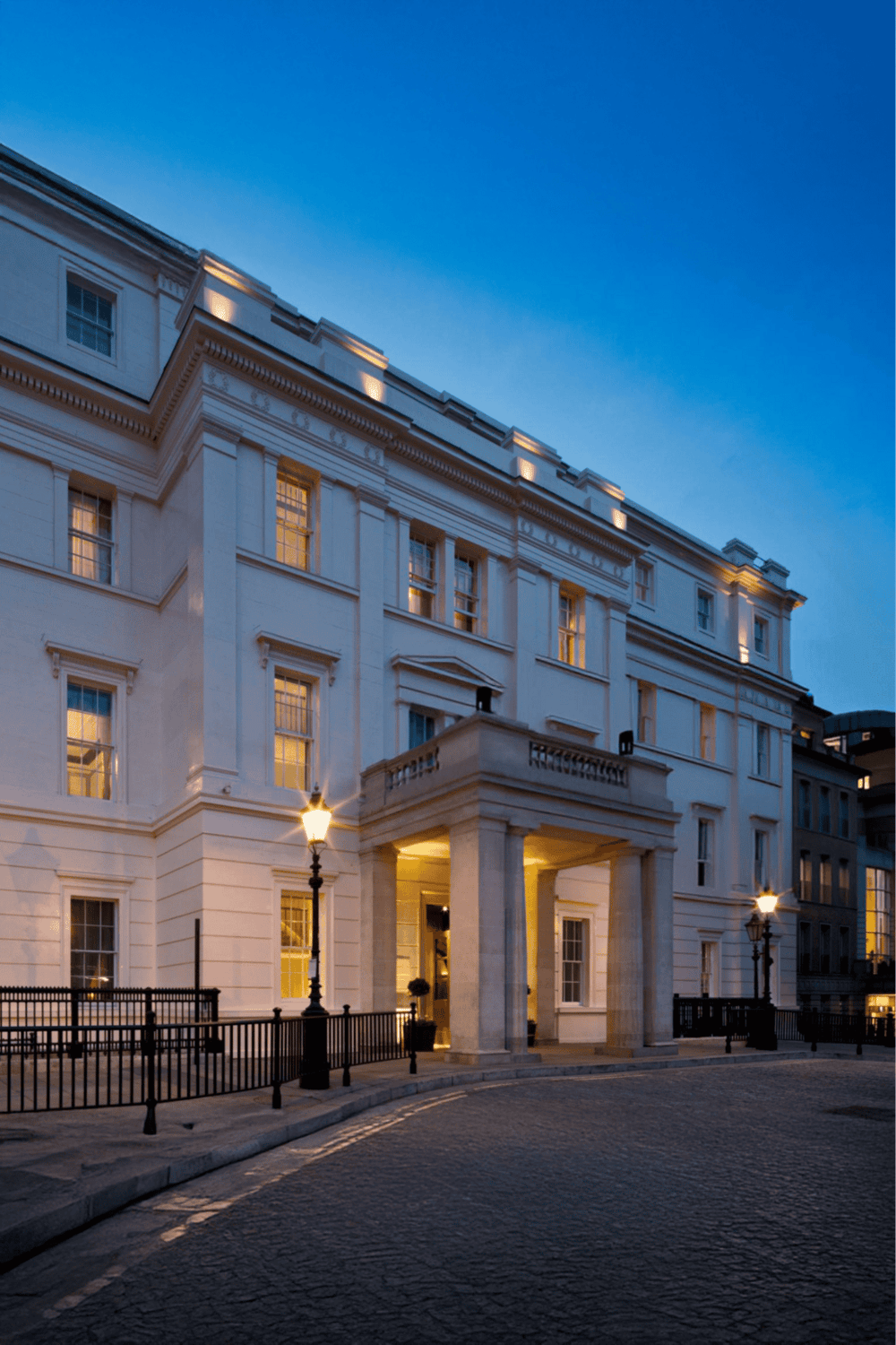 Elegant hotel exterior at dusk, luxury accommodations, historic architecture, city nightlife, peaceful evening ambiance.