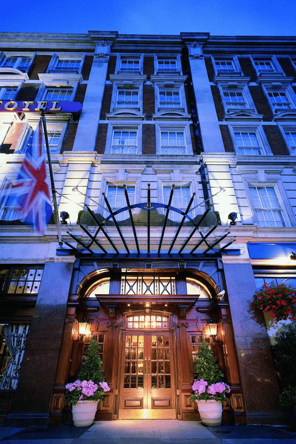 Upscale hotel facade with illuminated entrance, elegant architecture, and vibrant flowers for travel and accommodation SEO.