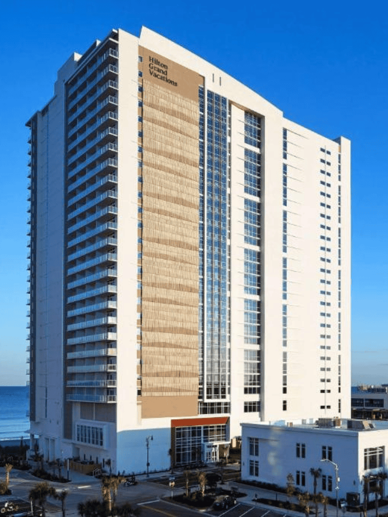 Modern Hilton Grand Vacations hotel tower in a coastal city with ocean view.