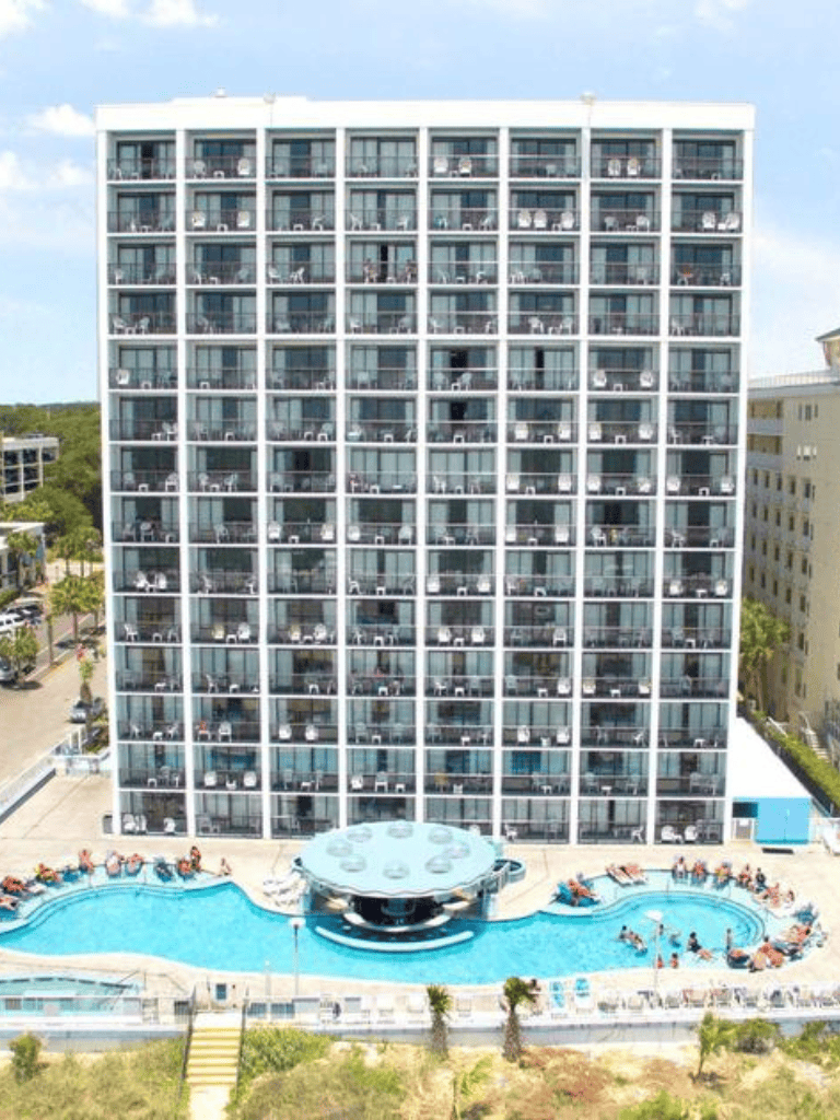 Modern hotel building with pool, balcony views,and sunbathers at QuestForDirections.