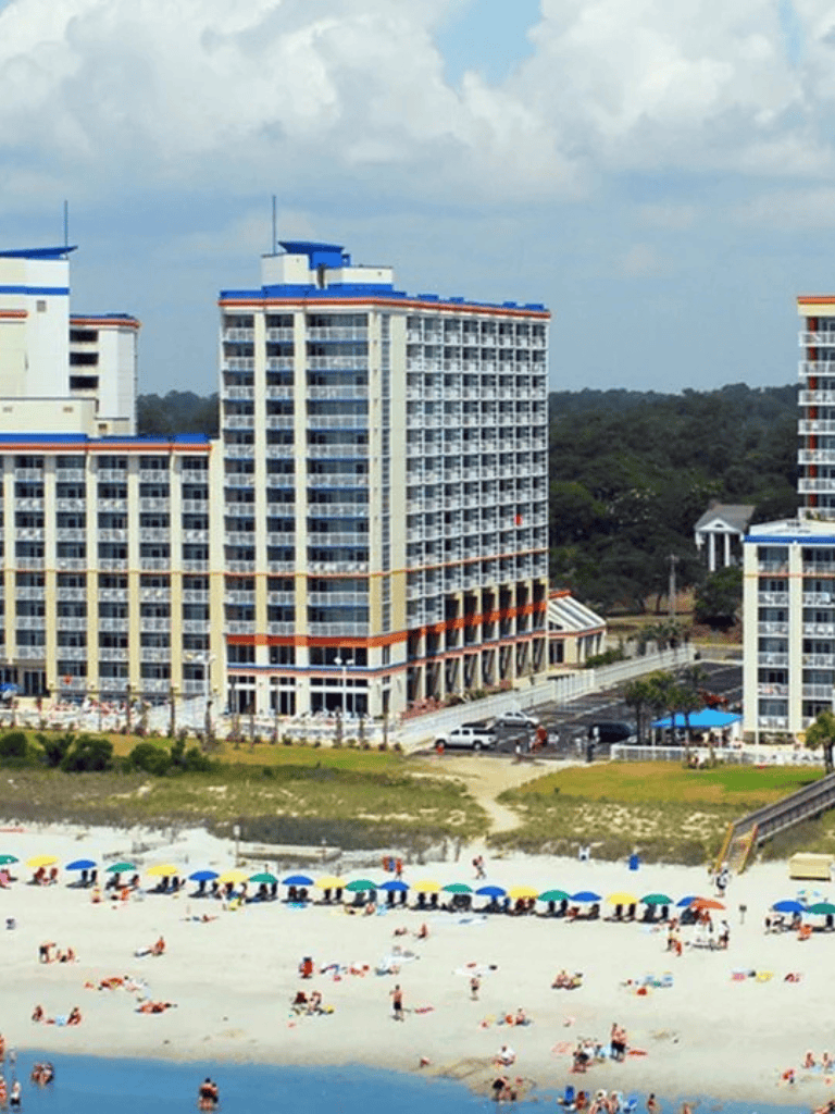 Modern beachfront hotel with colorful umbrellas and ocean views, offering amenities for travelers and vacationers.
