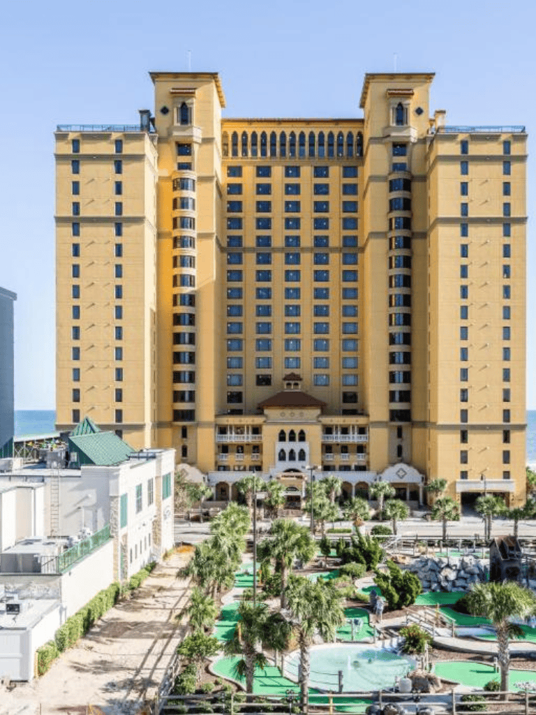 Luxury hotel with towering sky-rise structure and tropical pool area.