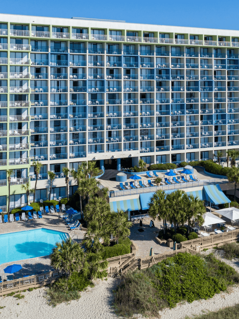 Modern beachfront hotel with multiple balconies and pool area, offering vacation accommodations.
