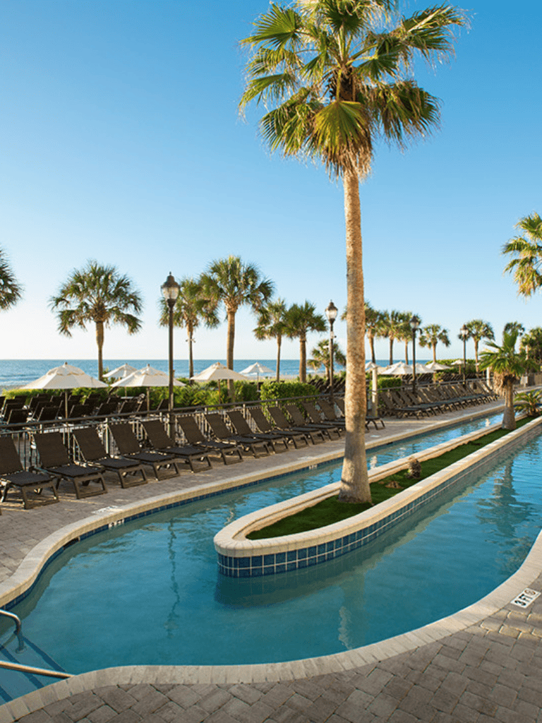 Relaxing beach resort with a pool, palm trees, and ocean view for vacation travel.