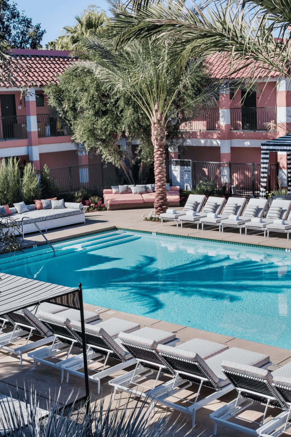 Modern hotel pool with lounge chairs and palm trees for relaxing vacations.