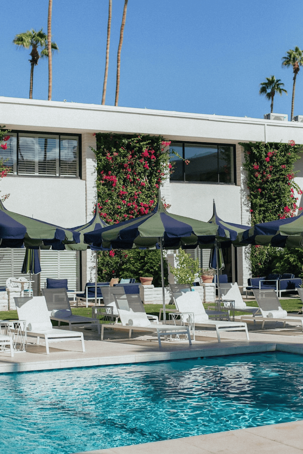 Luxurious modern hotel poolside area with palm trees and outdoor lounge chairs in sunny California.