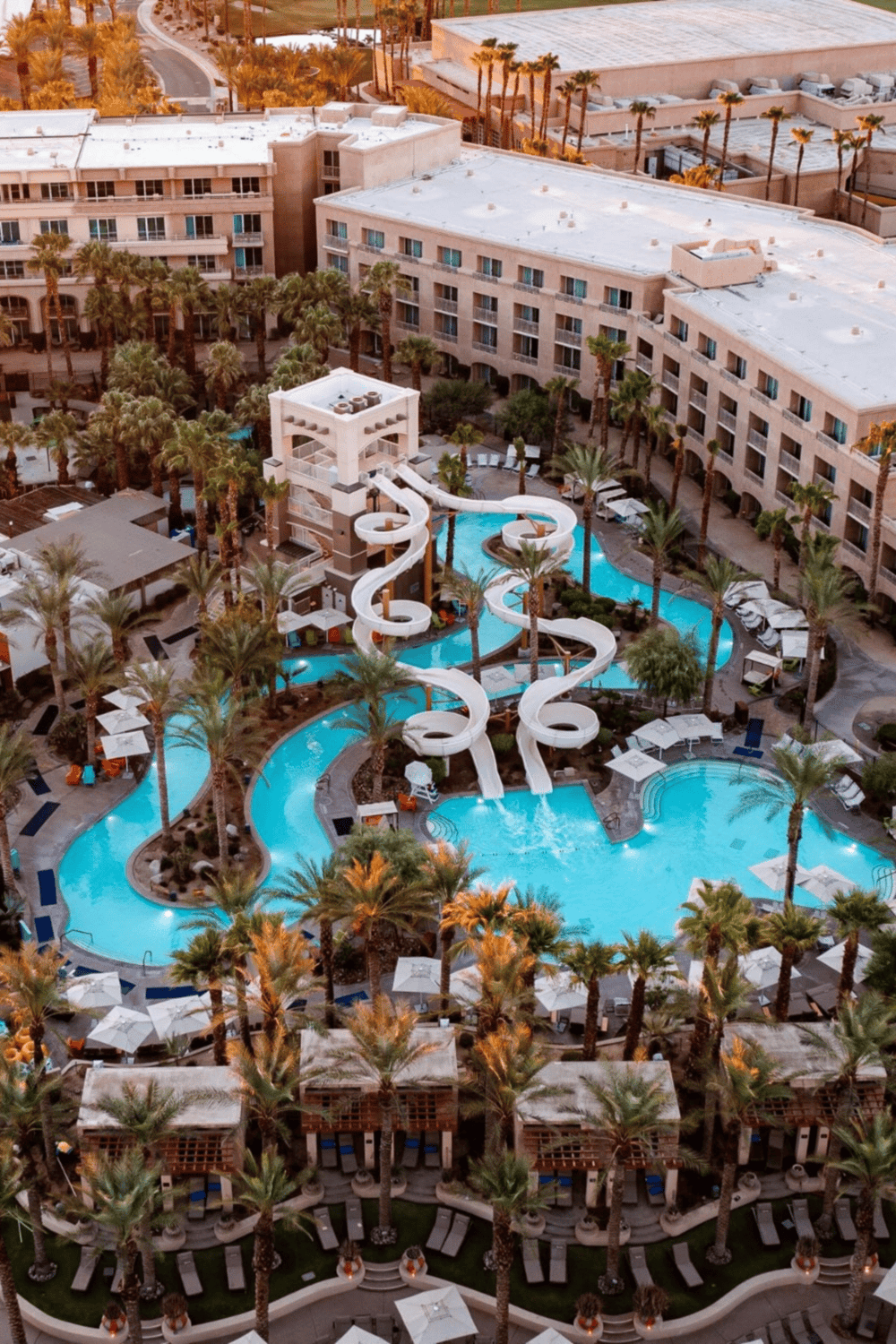 Luxurious hotel with water slides and outdoor pools in a palm tree oasis, perfect for relaxation and family fun.