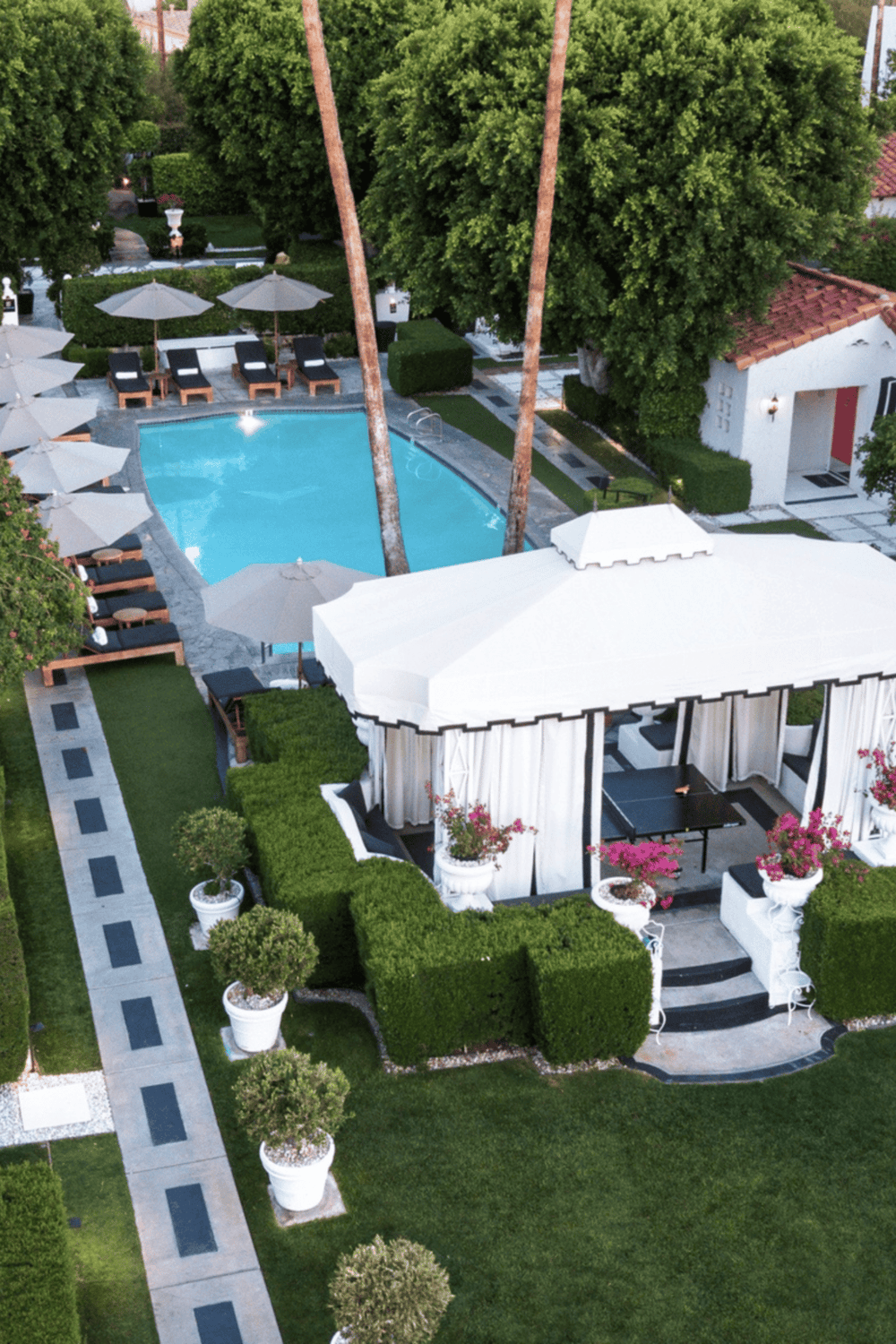 Lush outdoor pool area with cabanas and shaded lounge chairs at a luxury resort.