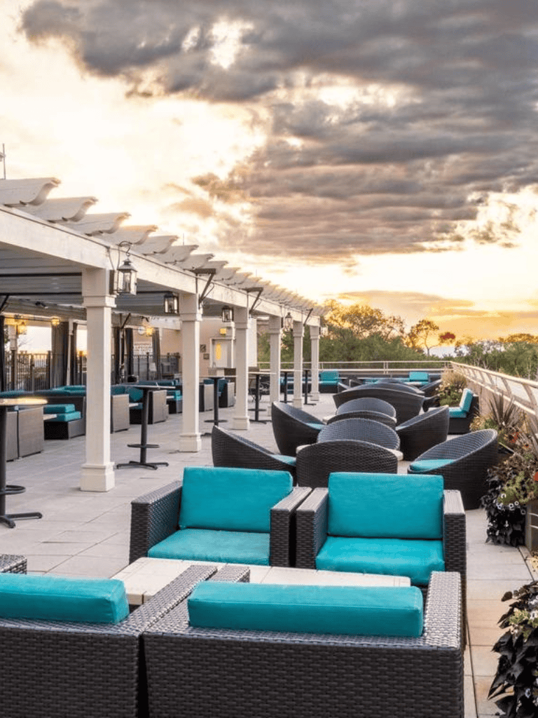 Outdoor rooftop bar with stylish seating and sunset view for relaxing and socializing.