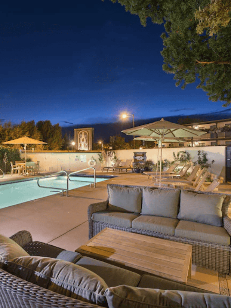 Relaxing outdoor pool area with lounge chairs and umbrellas at night, perfect for summer vacations.