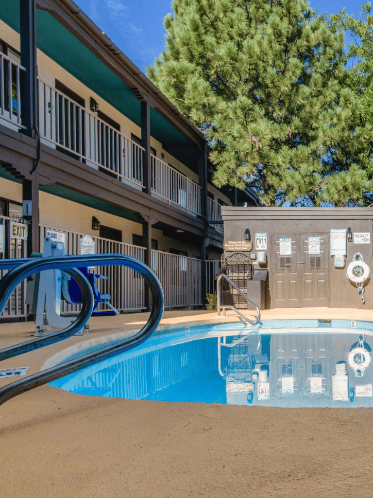 Clean hotel swimming pool with railing, pool safety equipment, and surrounding deck area.