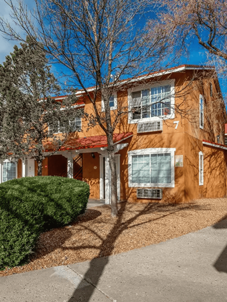 Charming orange apartment building with trees in front, sunny day, residential neighborhood, QuestForDirections.