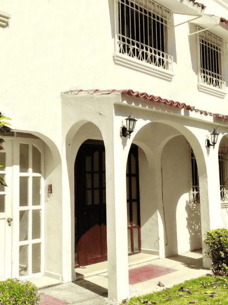 Charming Mediterranean-style house with arches, white walls, and decorative window grilles.