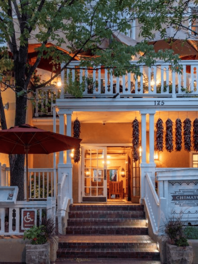 Charming boutique hotel entrance with cozy outdoor seating and vibrant hanging chili peppers.