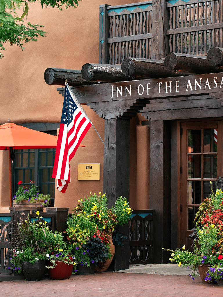 Charming inn exterior with rustic wood accents, American flag, and colorful planters for a cozy hospitality vibe.