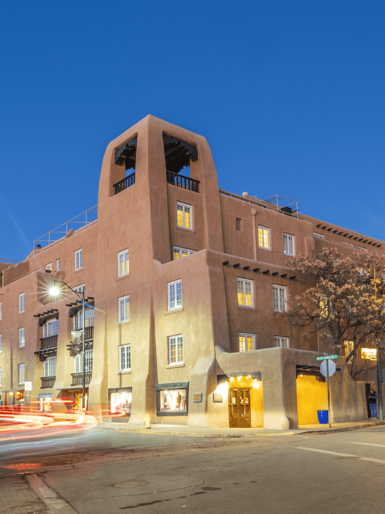 Adobe-style building with Southwestern architecture at dusk, illuminated windows, and a clear evening sky.