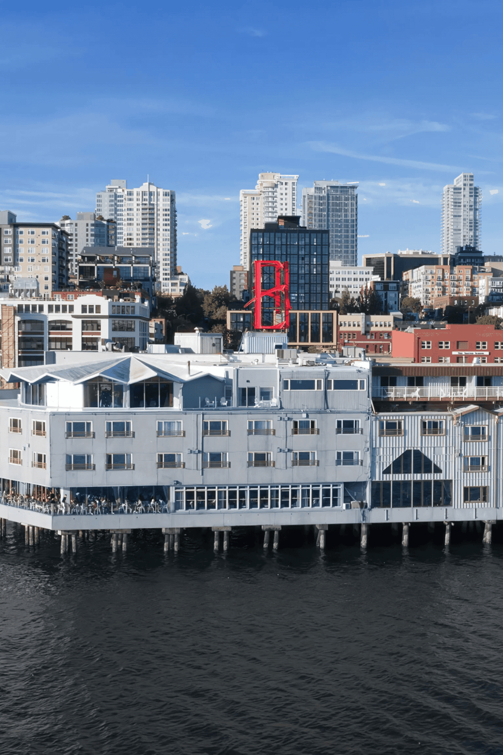 Bright city skyline with waterfront restaurant and iconic red bridge sculpture in San Francisco.