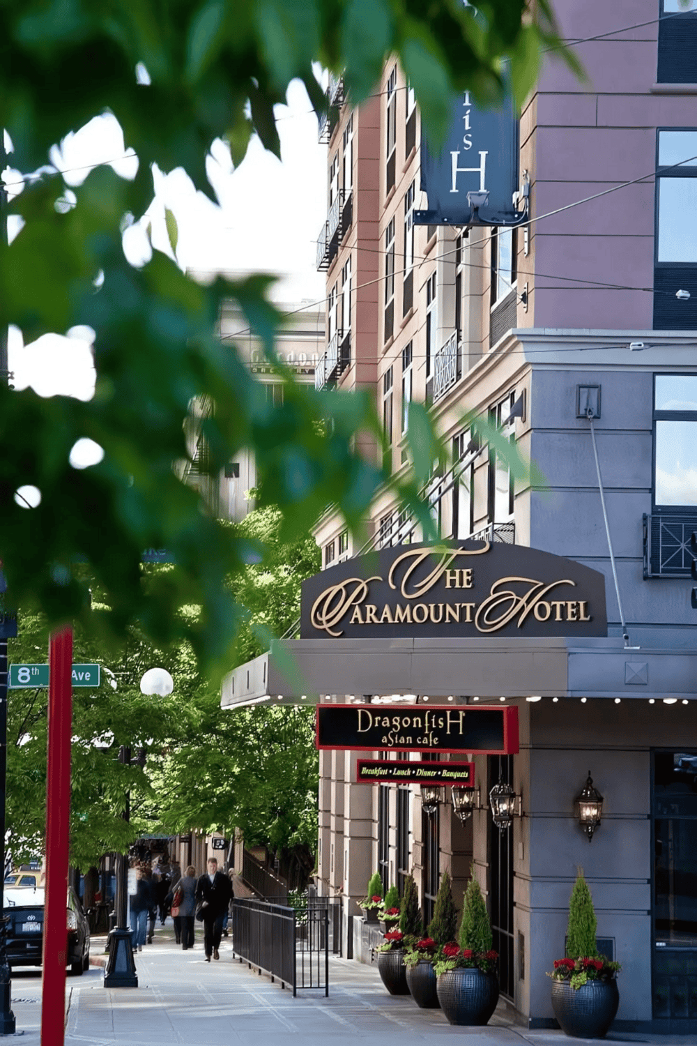 - Modern urban hotel exterior with greenery and sidewalk cafes.