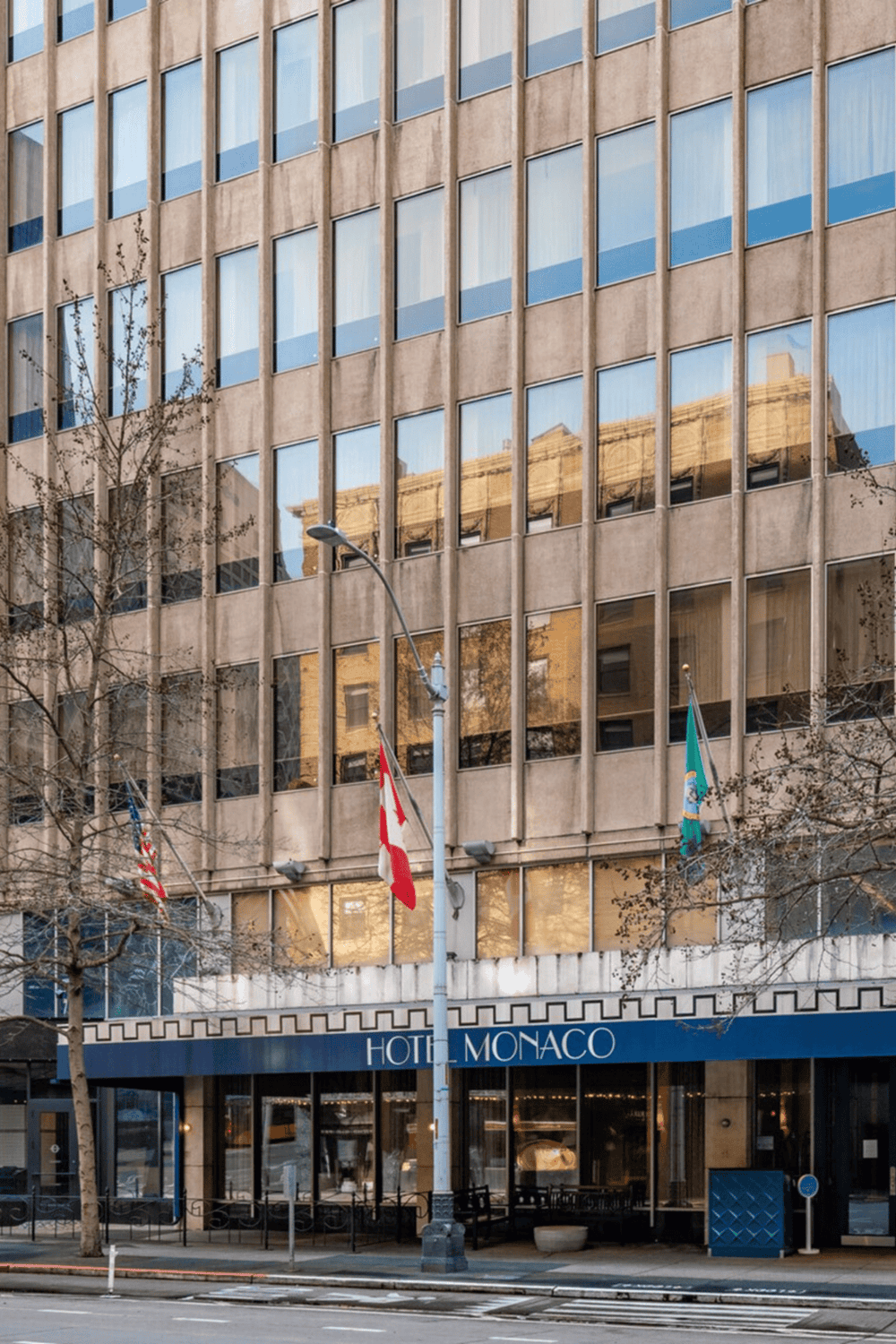 Luxury hotel Monaco with glass windows reflecting surrounding cityscape, situated in downtown urban area.