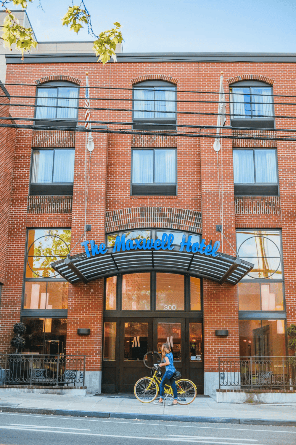 Modern brick hotel exterior with cyclist and vibrant signage, highlighting local travel and accommodation options.