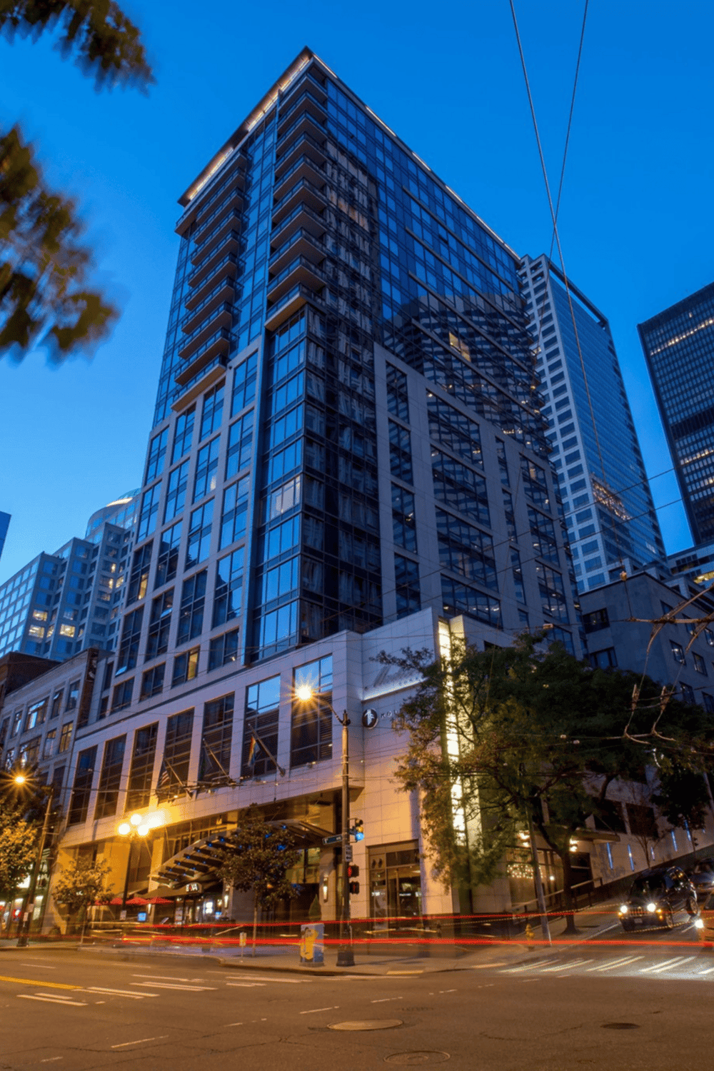 Modern downtown skyscraper in city at dusk with illuminated streets and busy traffic.