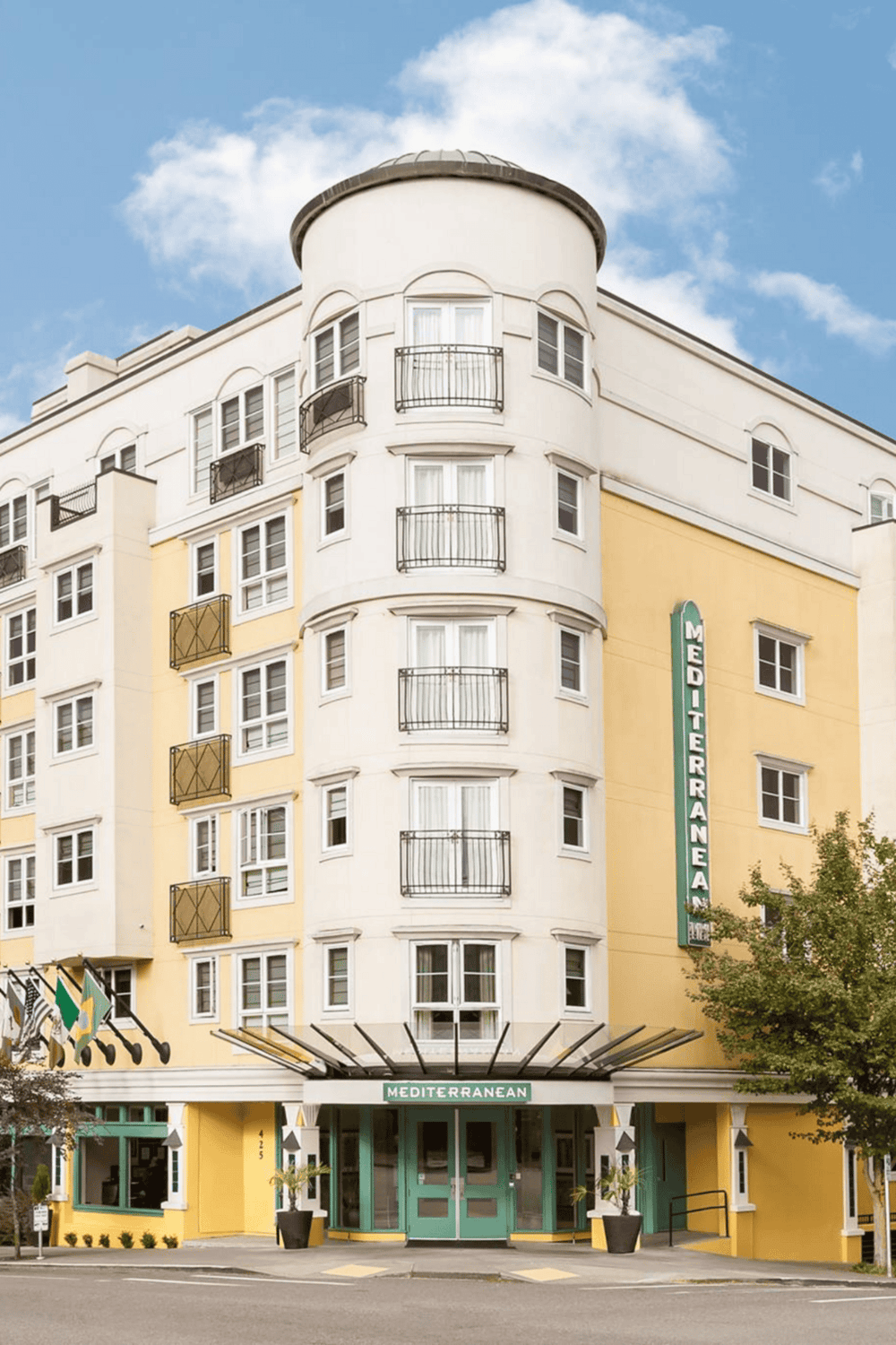 Modern hotel exterior with yellow and white facade, balconies, and Mediterranean decor, showcasing travel destination options.