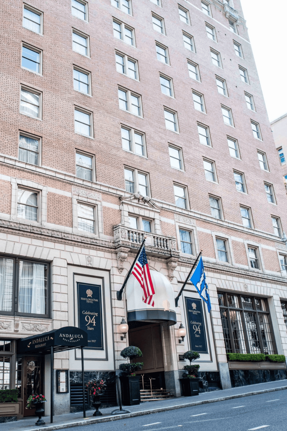 An inviting hotel entrance with flags and signage, located in a tall, historic brick building in the city center.