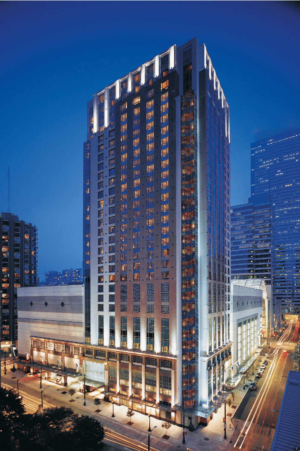 Modern high-rise hotel in downtown cityscape lit at night for luxury stay.